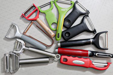 A group of vegetable peelers on a grey surface