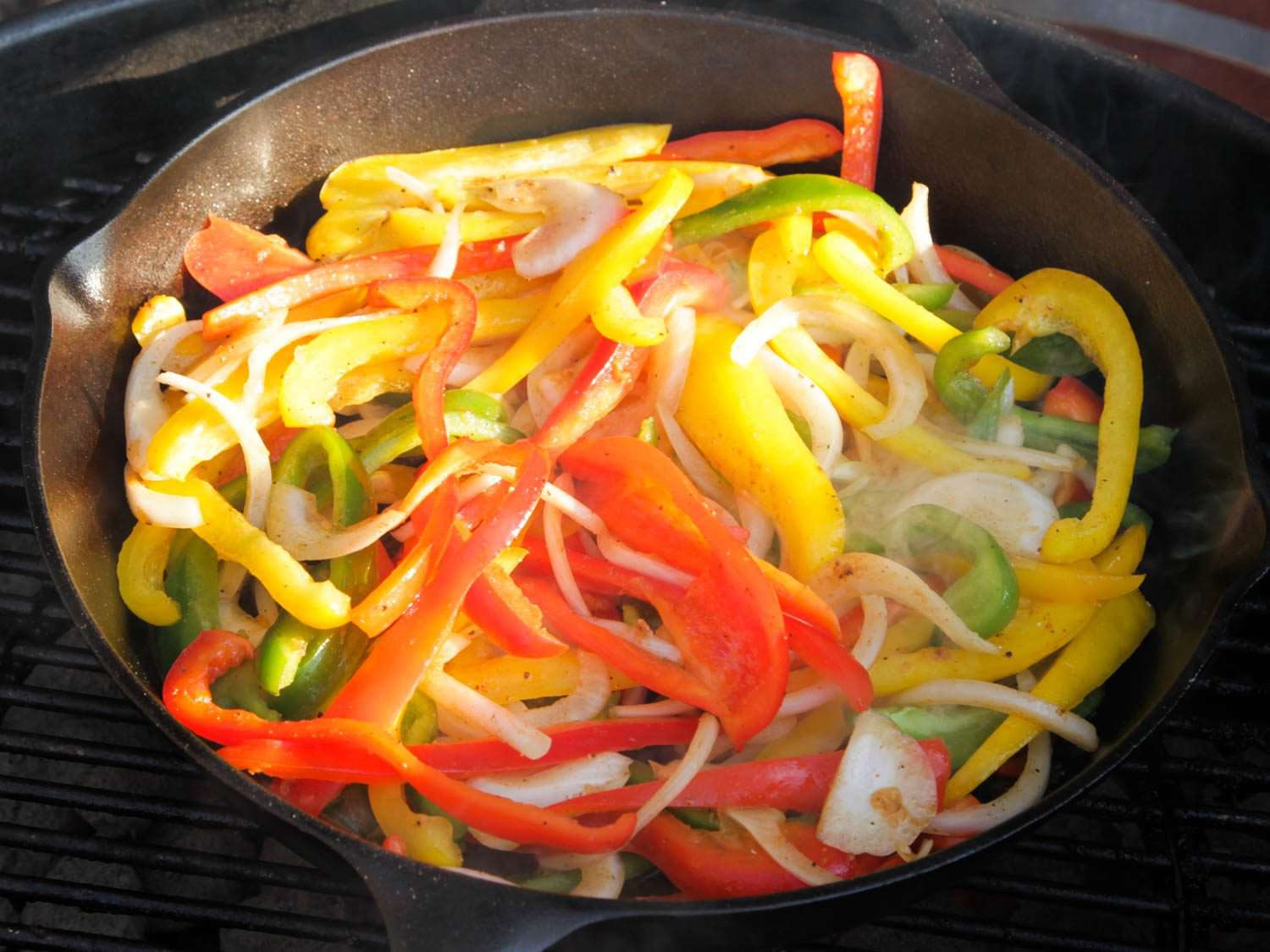 洋葱和辣椒在铸铁煎锅上烤制法士达。