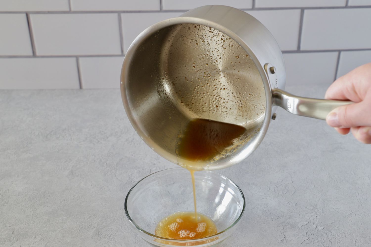 把褐色黄油从平底锅倒进小碗里的人