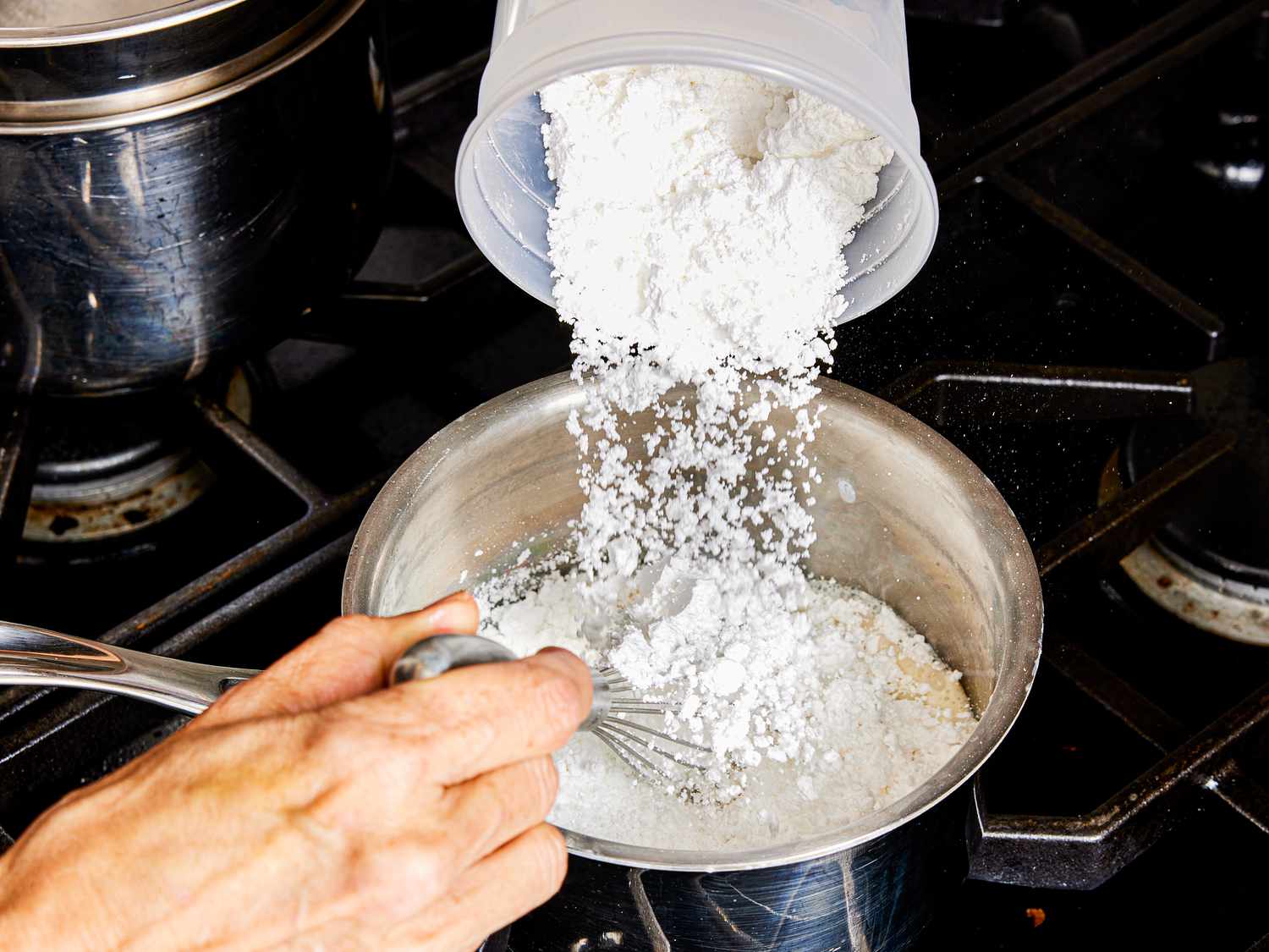 Overhead view of pouring sugar into a pot