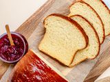 Overhead view of sliced brioche loaf on a cutting board next to jam