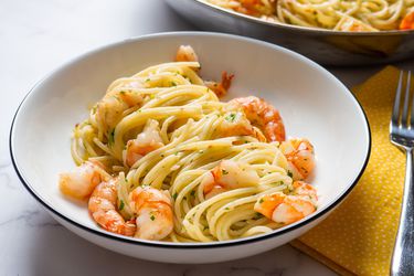 A bowl of shrimp scampi with pasta.