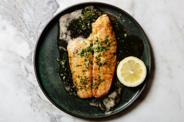 Sole Meuniere on a dark green plate on a marbled countertop