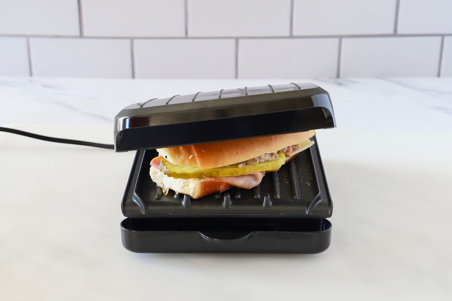 a small panini press pressing a cubano sandwich