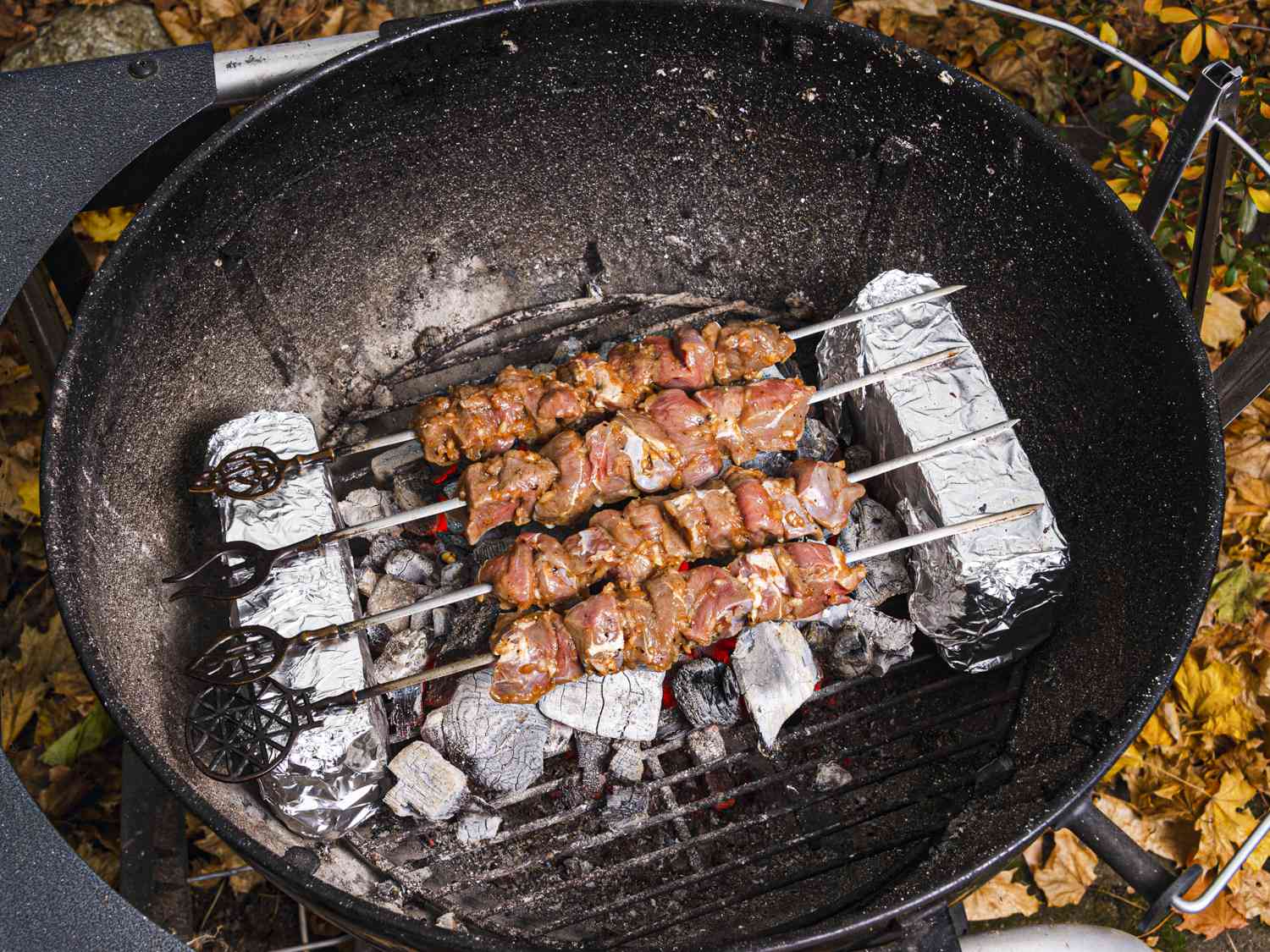 Overhead view of skewers on bricks in a charcoal grill