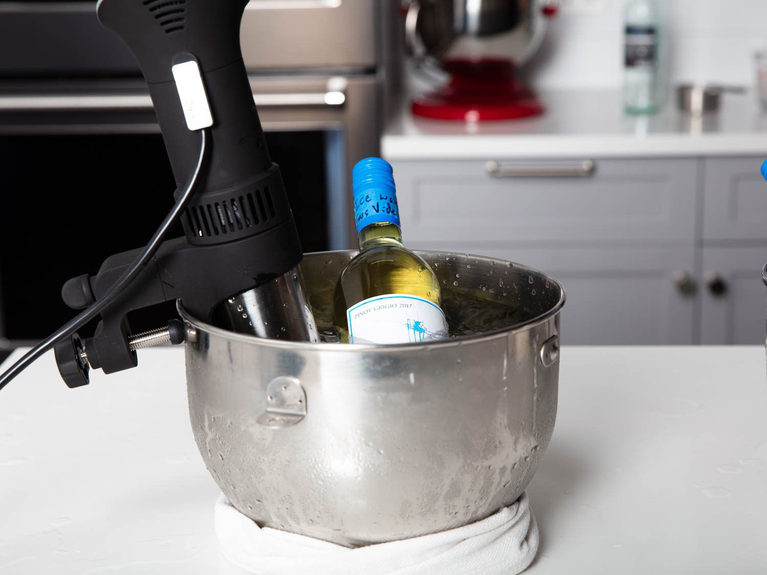 A bottle of white wine in a stand mixer bowl fitted with an immersion circulator.