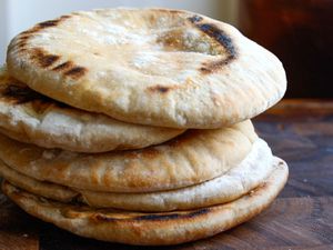 A stack of pitas on a wooden surface