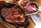 Cochinita Pibil wrapped in banana leaves with pickled diced red onion and tortillas.