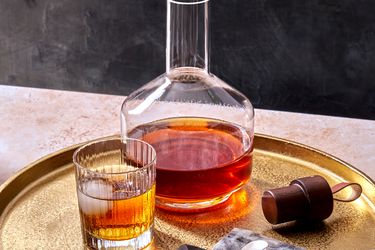 spiced rum in a glass with a decanter filled with the full batch