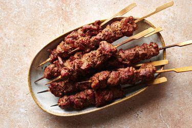 Skewers of spicy cumin lamb (yang rou chuan) on an oval platter.