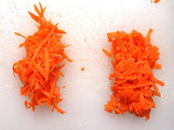 两堆磨碎的胡萝卜放在砧板上。其中一种以直角放置，由较短的碎片组成。