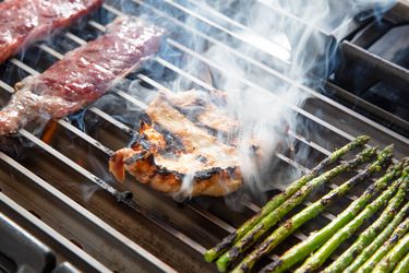 Meat and vegetables cooking on the GrillGrate