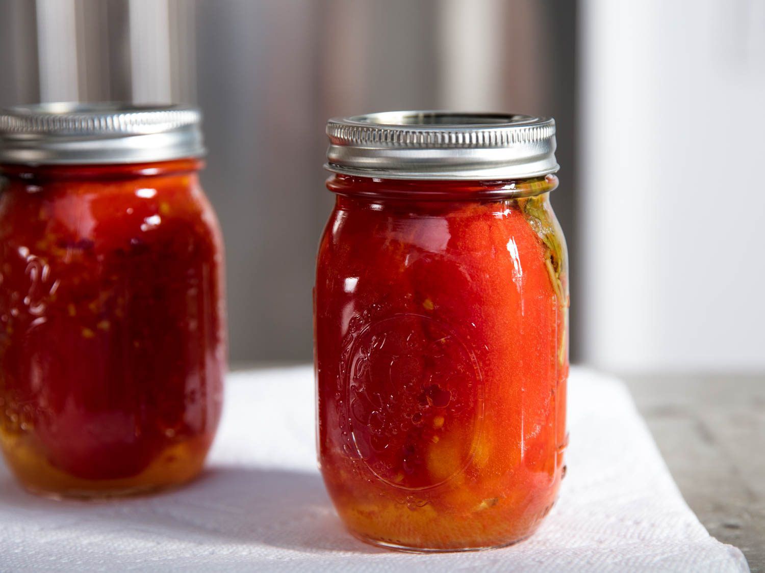 Two sealed mason jars filled with preserved tomatoes.