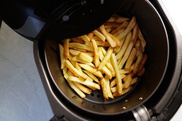 An air fryer basket containing fries