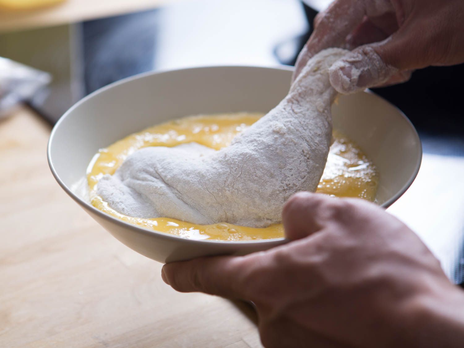 把撒了面粉的鸡腿浸在打好的鸡蛋里