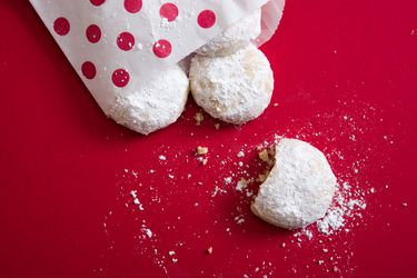 雪球饼干从一个圆点袋子里溢出来，洒在红色的工作台上