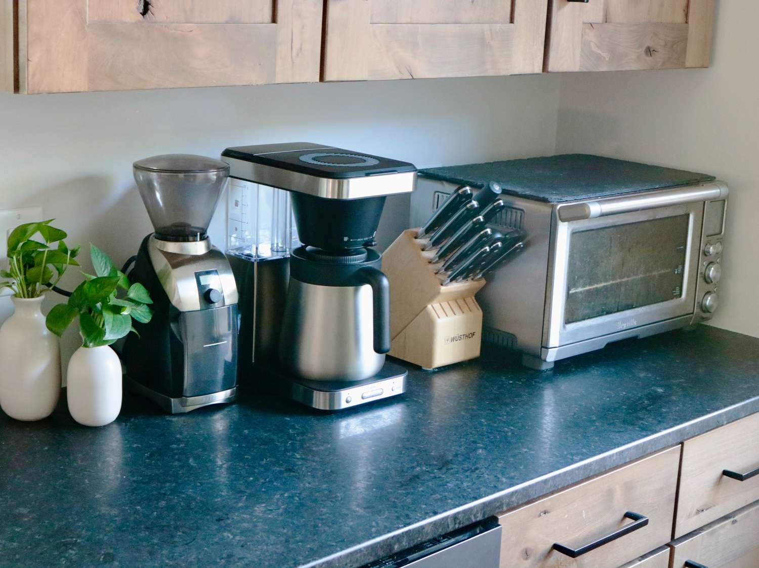 an OXO 8-Cup Brewer on a counter with a grinder, knife block, and toaster oven