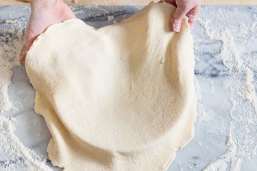 Laying a round of flaky, all-butter pie dough in a pie pan.