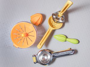 four different styles of citrus juicers on a white surface