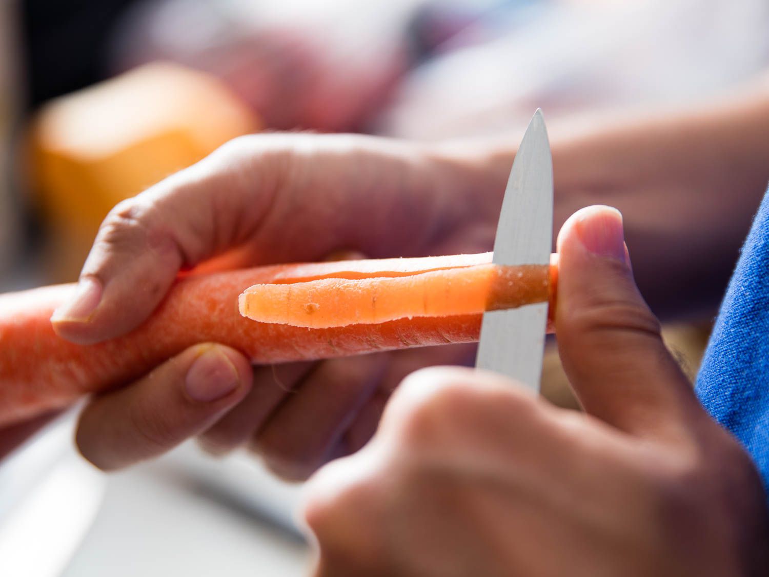 A pairing knife peeling a carrot