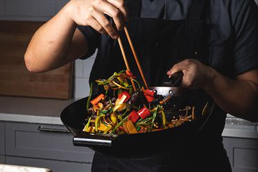 A chef stir-frying colorful vegetables