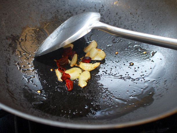 辣椒和大蒜在锅里炸，用金属刮刀翻炒。