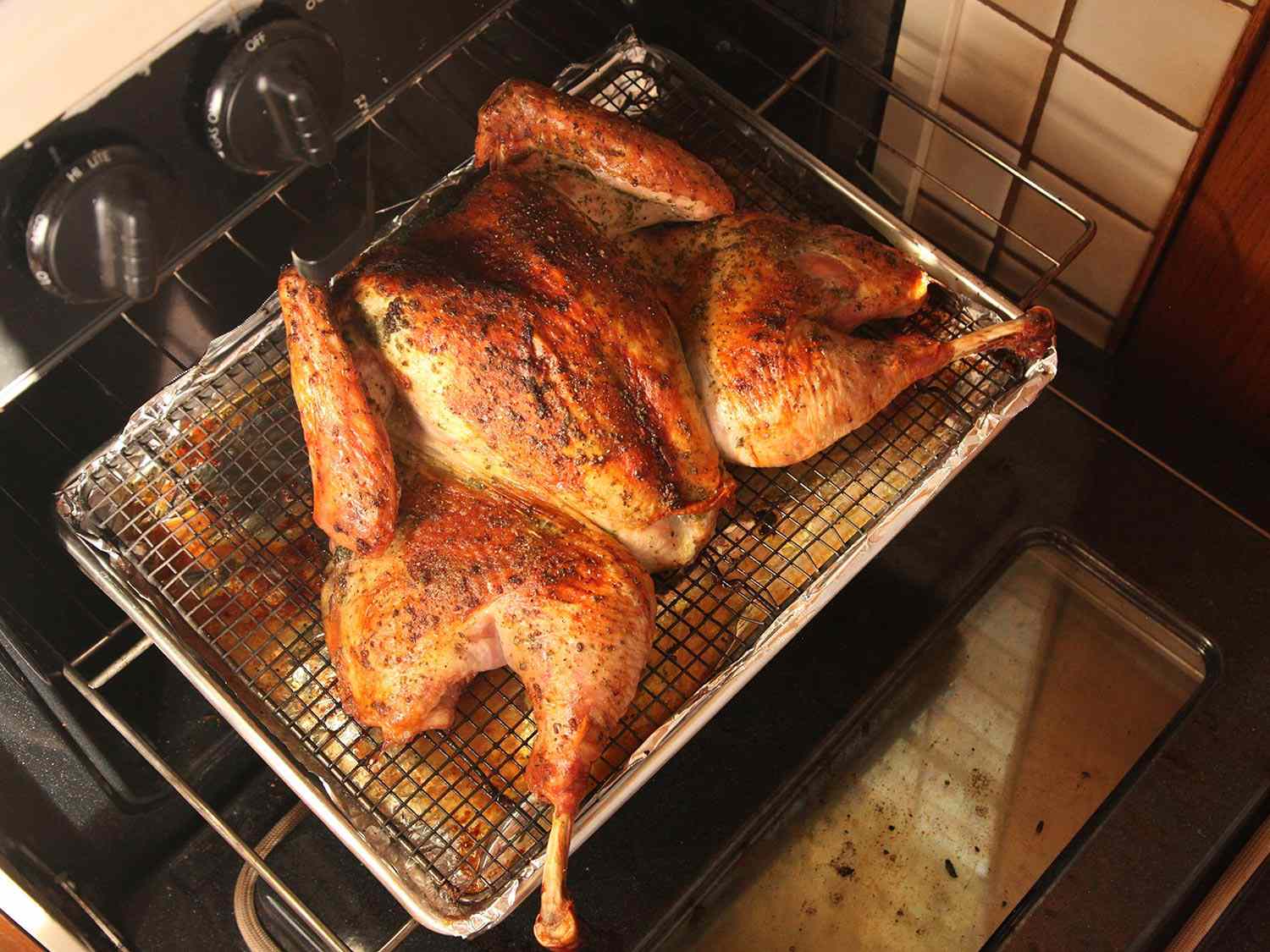 Spatchcocked roasted turkey being pulled from an oven