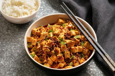 A bowl of spicy mapo tofu with a side of rice.