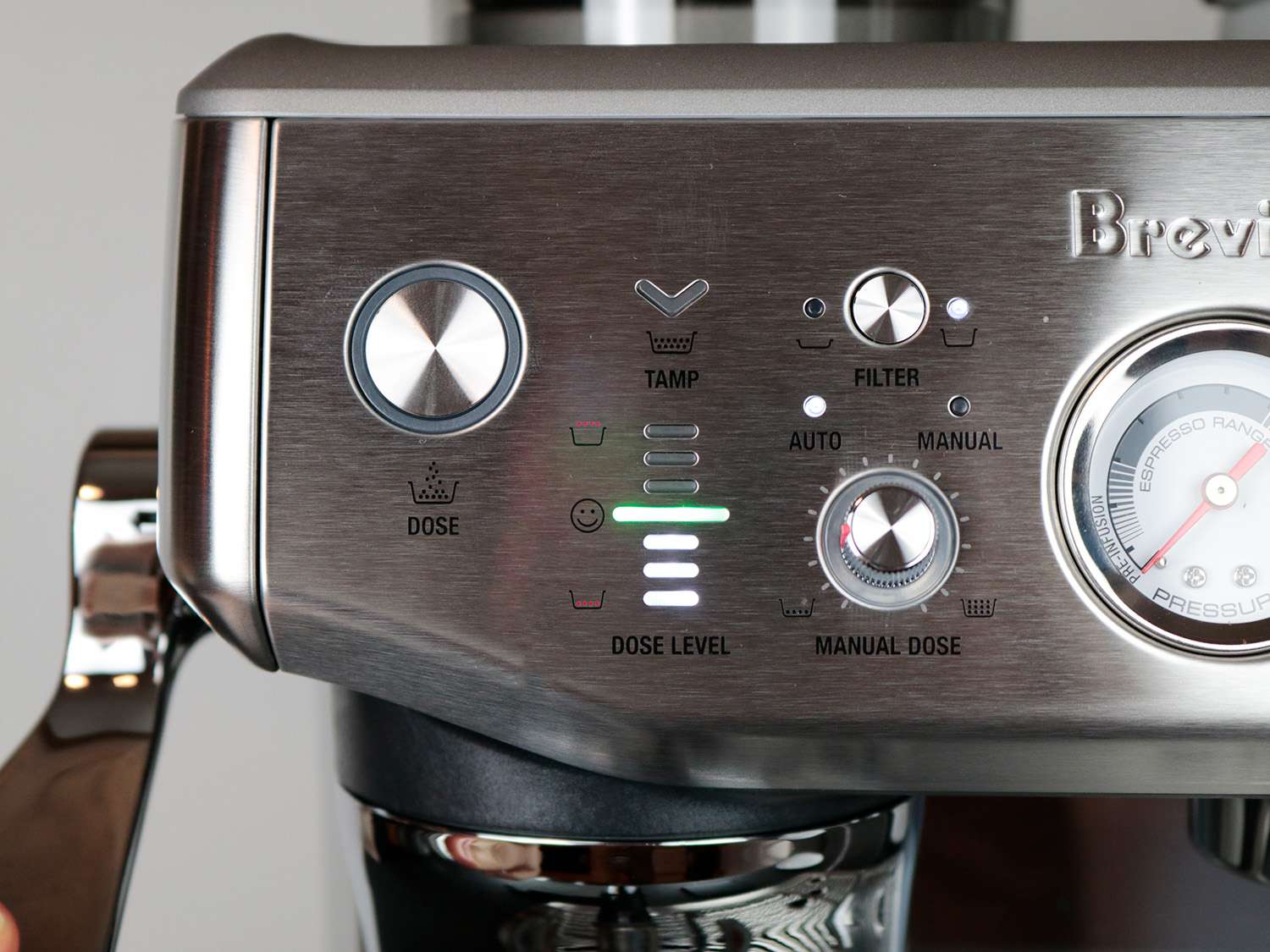 the font of an espresso machine showing a number of dials and switches and a green light indicating proper dosage