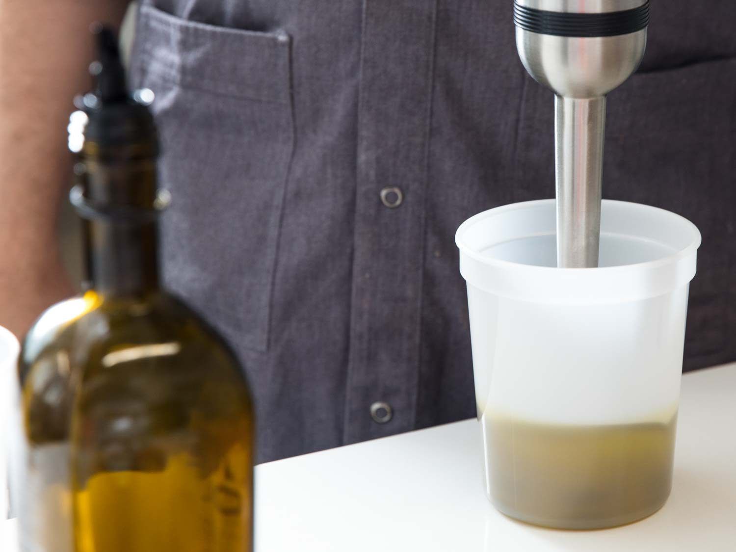 用浸入式搅拌器在透明的塑料容器中搅拌橄榄油乳液