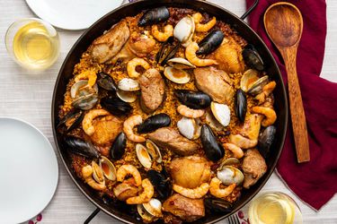 一锅烤海鲜饭放在桌子上，有贻贝，虾，鸡肉和蛤蜊。