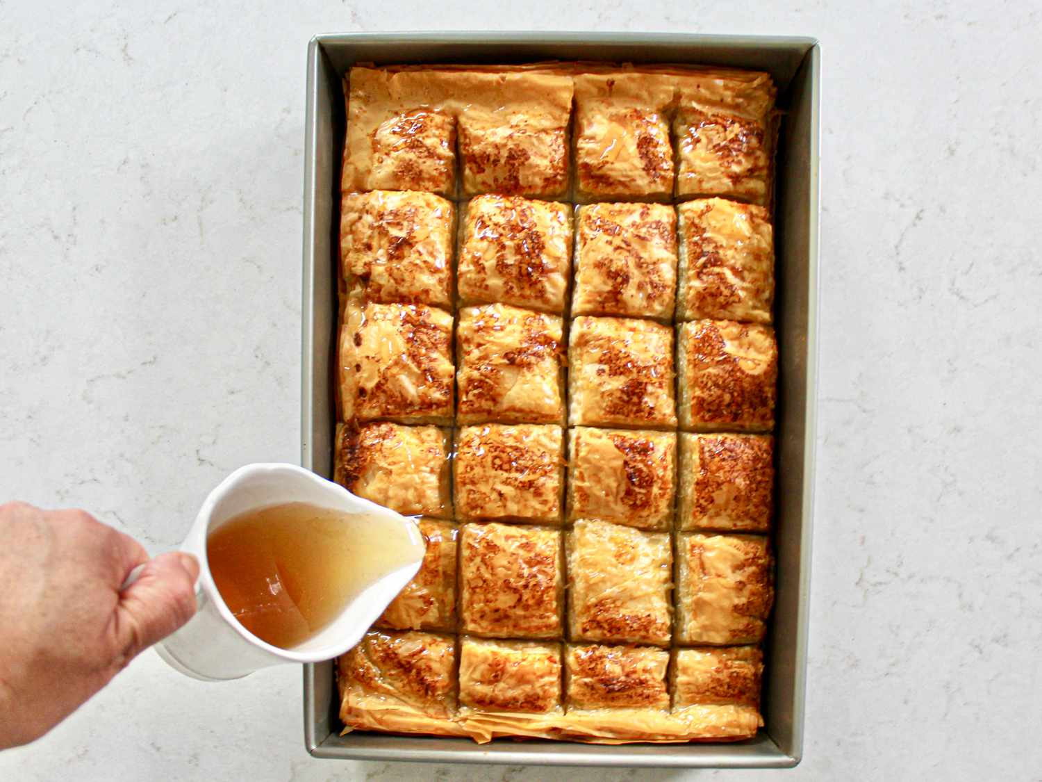 Pouring simple syrup over baklava