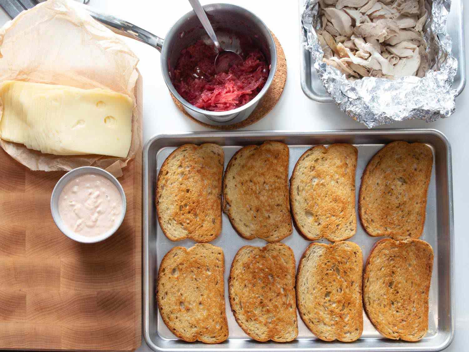 火鸡鲁本三明治的配料开销:烤黑麦面包、吃剩的烤火鸡、蔓越莓酸菜、俄罗斯调味品和瑞士奶酪。