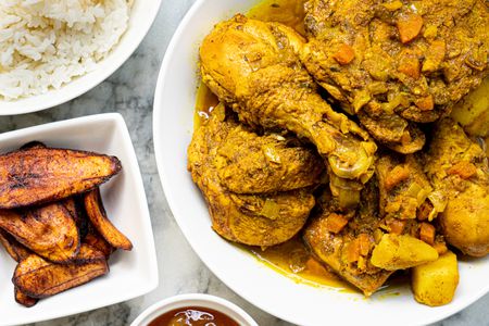 Overhead view of curry chicken with rice and fried plantains