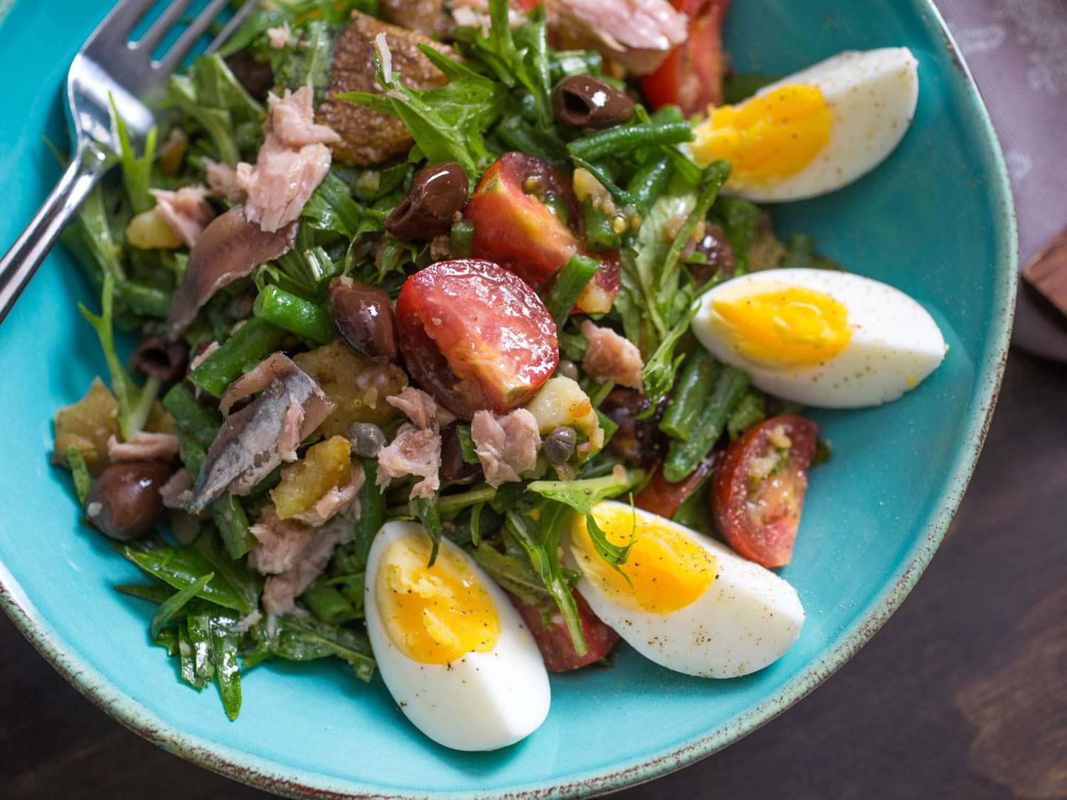 Overhead photo of nicoise salad in teal serving bowl.