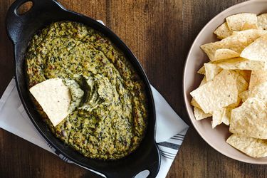 Overhead of vegan spinach dip served with a bowl of tortilla chips.