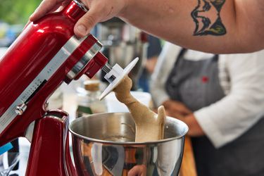 A hand holding a red stand mixer's tilt-head upright