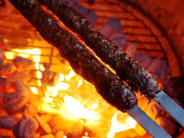 两根阿达纳烤肉串高举在熊熊燃烧的炭火上。