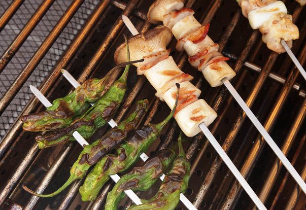 peppers, mushrooms, scallions, and chicken on skewers on a grill