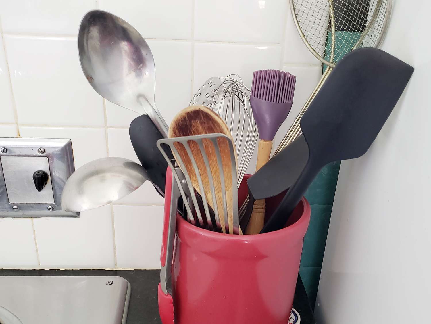 a red utensil crock filled with different utensils