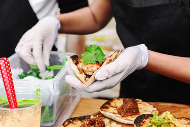 hands wearing gloves prepare tacos