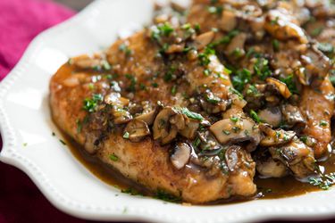 A chicken marsala covered in mushroom and resting on a plate