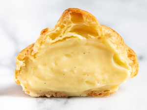 A choux pastry puff filled with pastry cream, cut in half so you can see the vanilla pastry cream