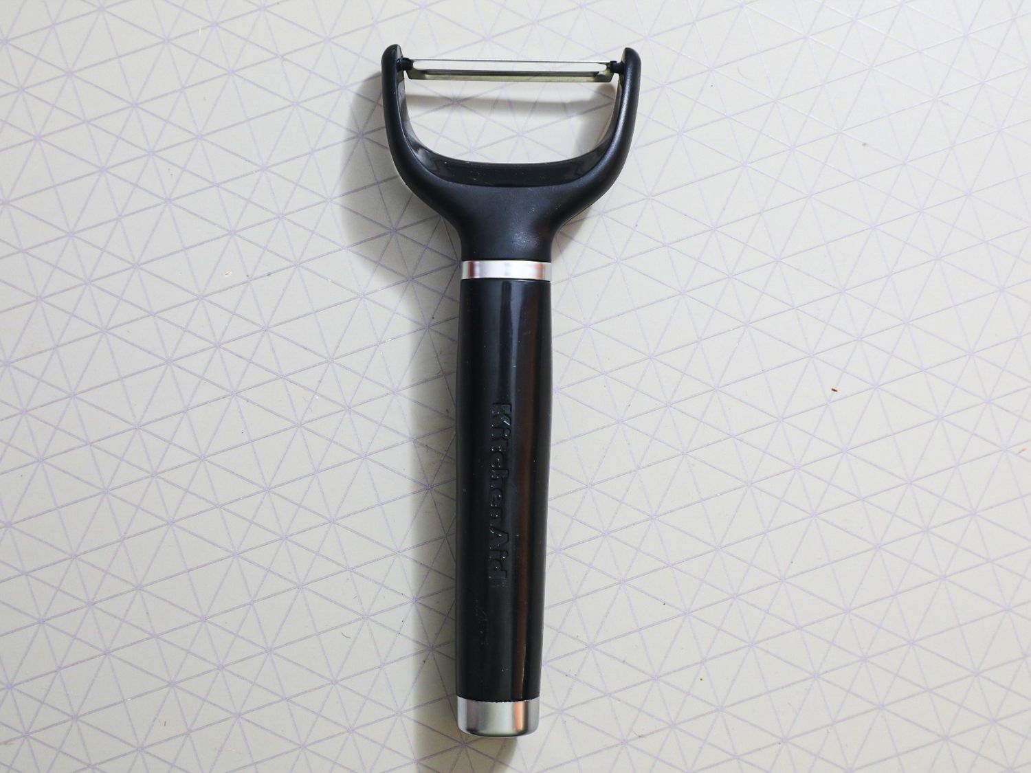 A black KitchenAid peeler on a grey surface