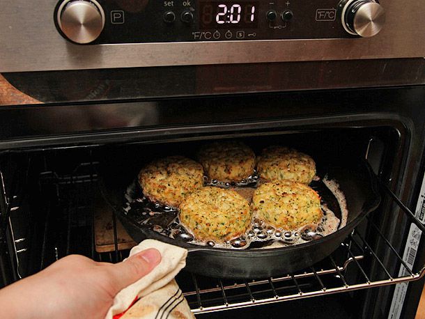 将盛有五只蟹饼的铸铁煎锅放入烤箱烤制。