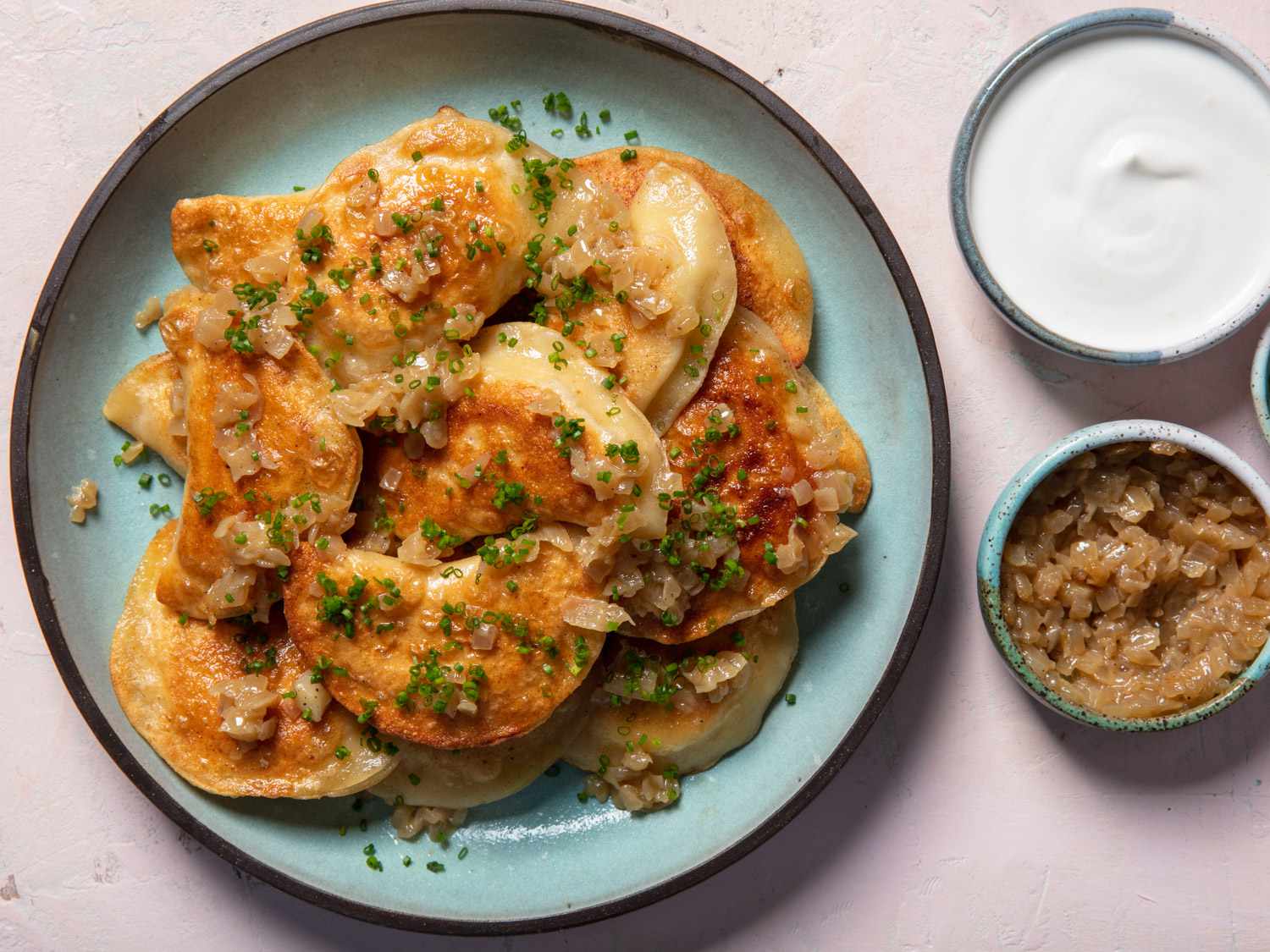 A serving plate of pierogi topped with onions and chives