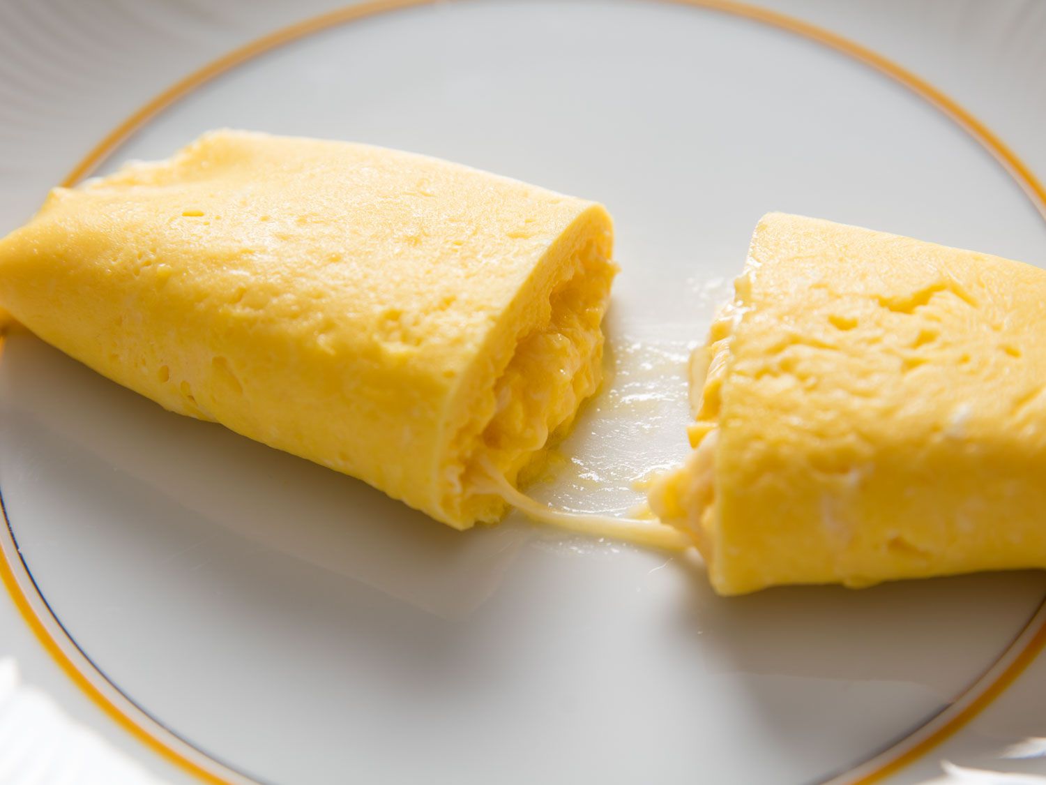 中间夹着奶酪的法式煎蛋卷，切开放在白色盘子里gydF4y2Ba