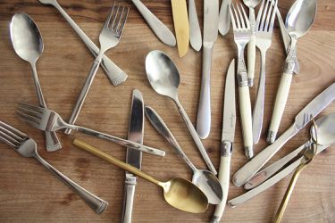 a bunch of silverware on a wooden surface