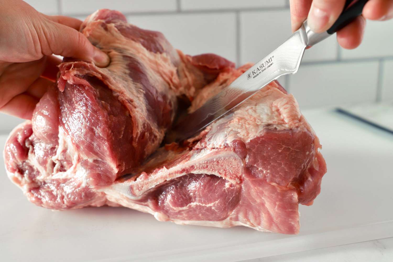 using a boning knife to remove the bone from a pork shoulder