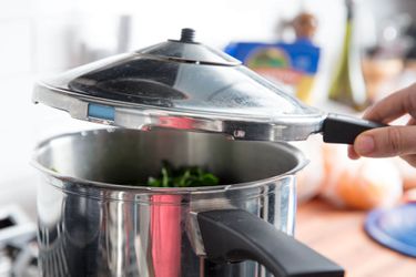 Lifting off a lid of a pressure cooker.